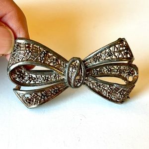 2 1/4” vintage bow pin. Silvertone and gold tone metal. Aged patina.